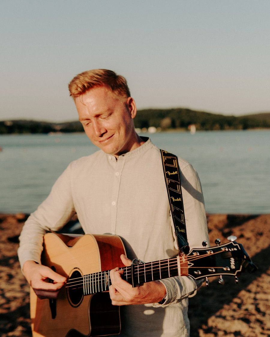 Marco Engel spielt Gitarre am Seeufer